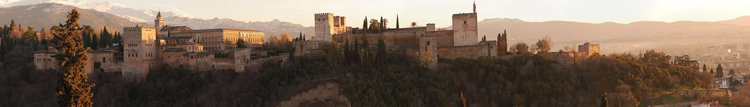 The Alhambra on its ridge above Granada at sunset, with the Sierra Nevada behind